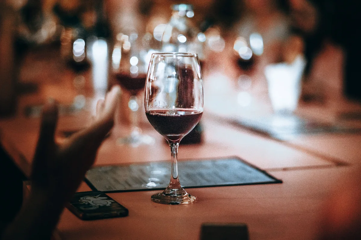 A glass of red wine poured at a long dinner table